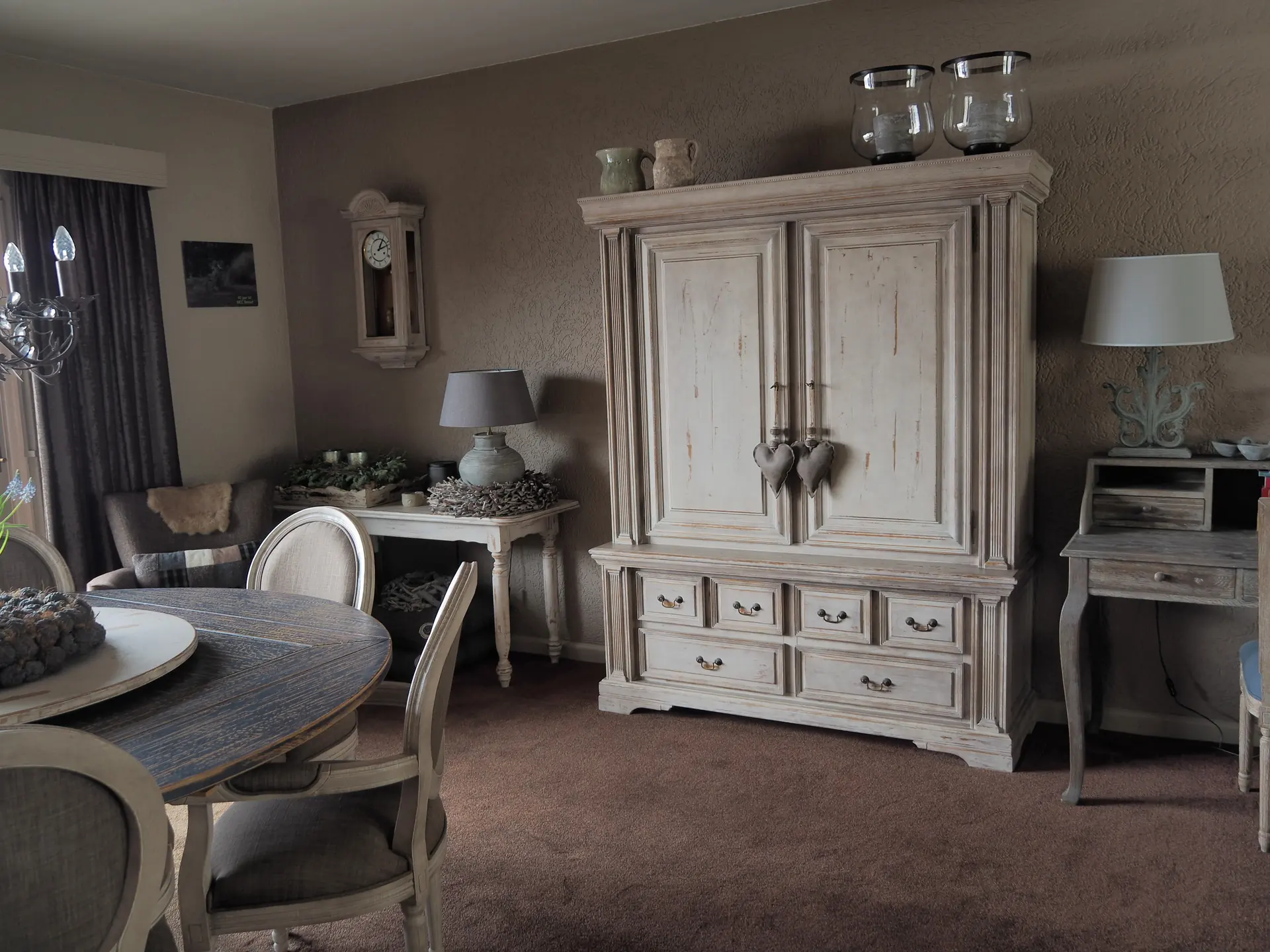 Woonkamer met een vergrijsde kast, tapijt en overgordijnen
