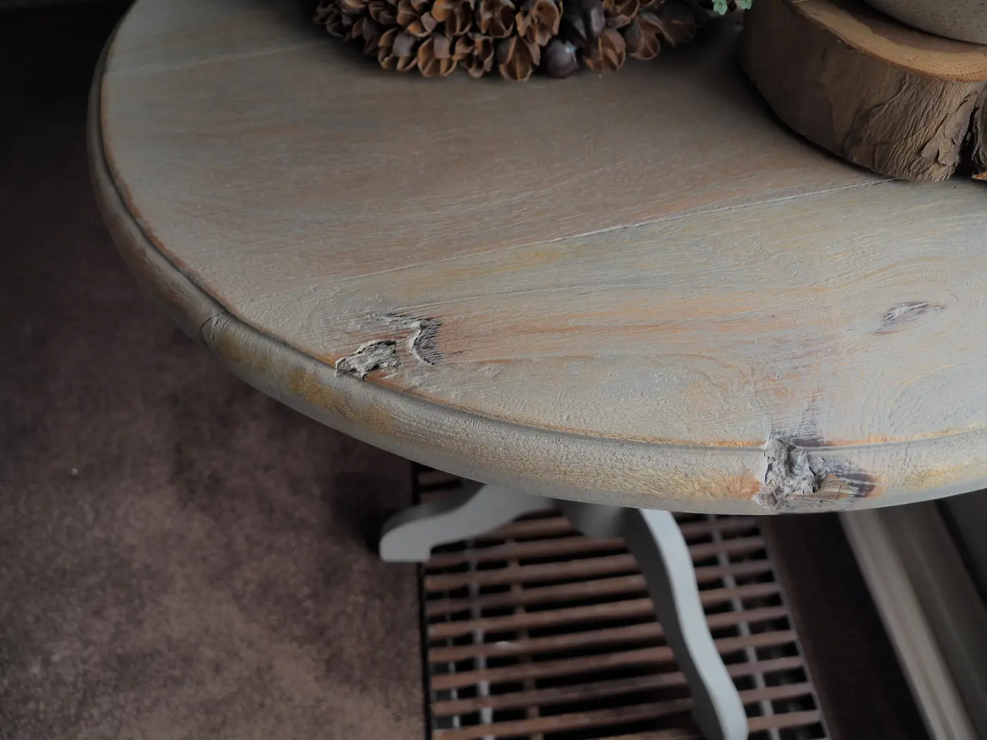 Detail van een ronde tafel, doorgeschuurd tot het hout weer zichtbaar is