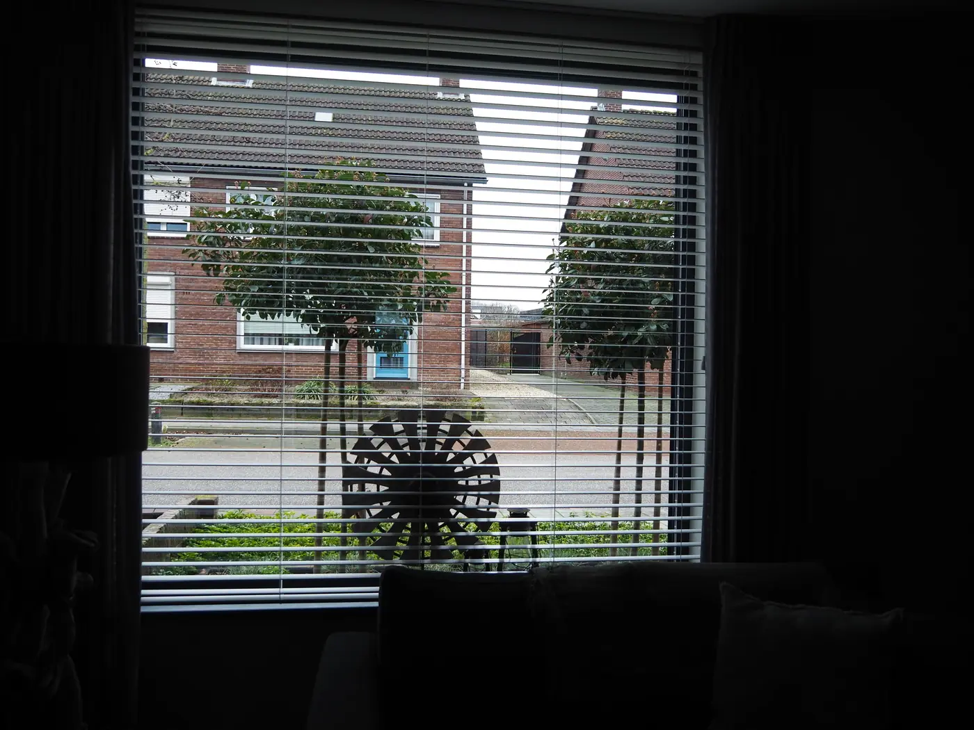 Houten jaloezieën voor een woonkamerraam met uitzicht op straat