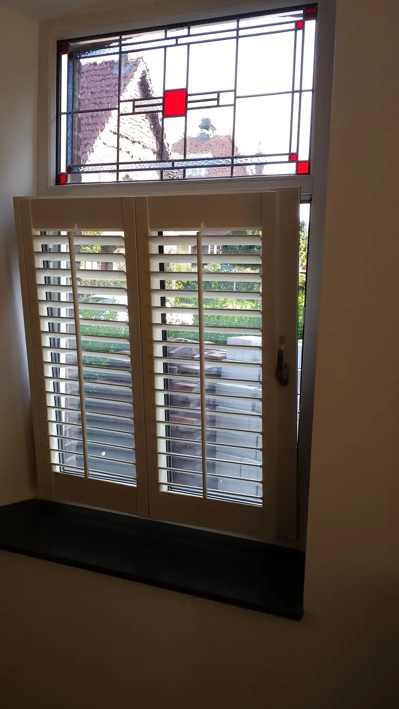 Shutters onder een glas-in-loodraam, in twee delen te bedienen