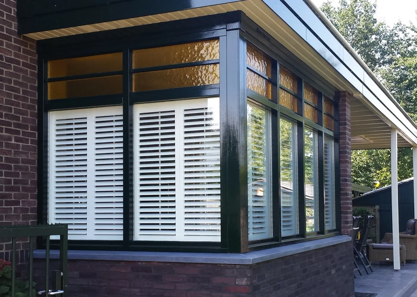 Serre met shutters achter de ramen, gezien vanaf de tuin