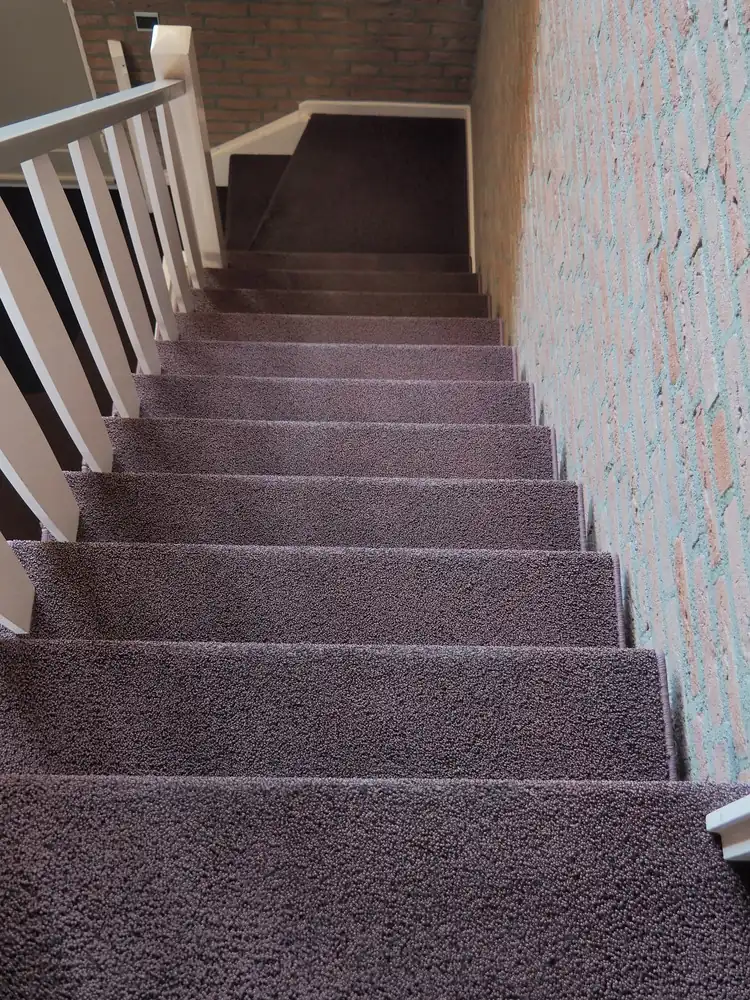 Taupe tapijt op een trap langs een behangen wand